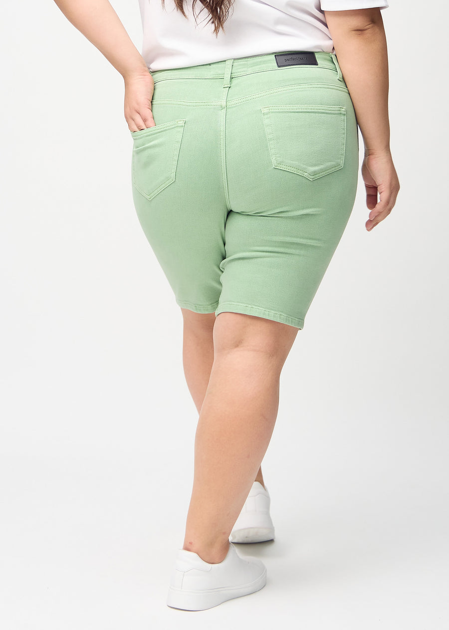 Hellgrüne skinny middle shorts von hinten an einem Plus-Size-Model gesehen, sodass man das gesamte Produkt sehen kann.