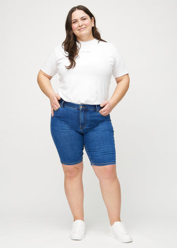 Ganzkörperbild eines Plus-Size-Models in dunklen Denim-skinny middle shorts.