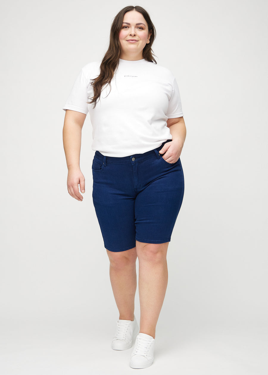 Ganzkörperbild eines Plus-Size-Models in dunkelblauen skinny middle shorts.