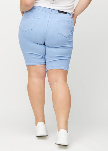 Hellblaue skinny middle shorts von hinten an einem Plus-Size-Model gesehen, sodass man das gesamte Produkt sehen kann.