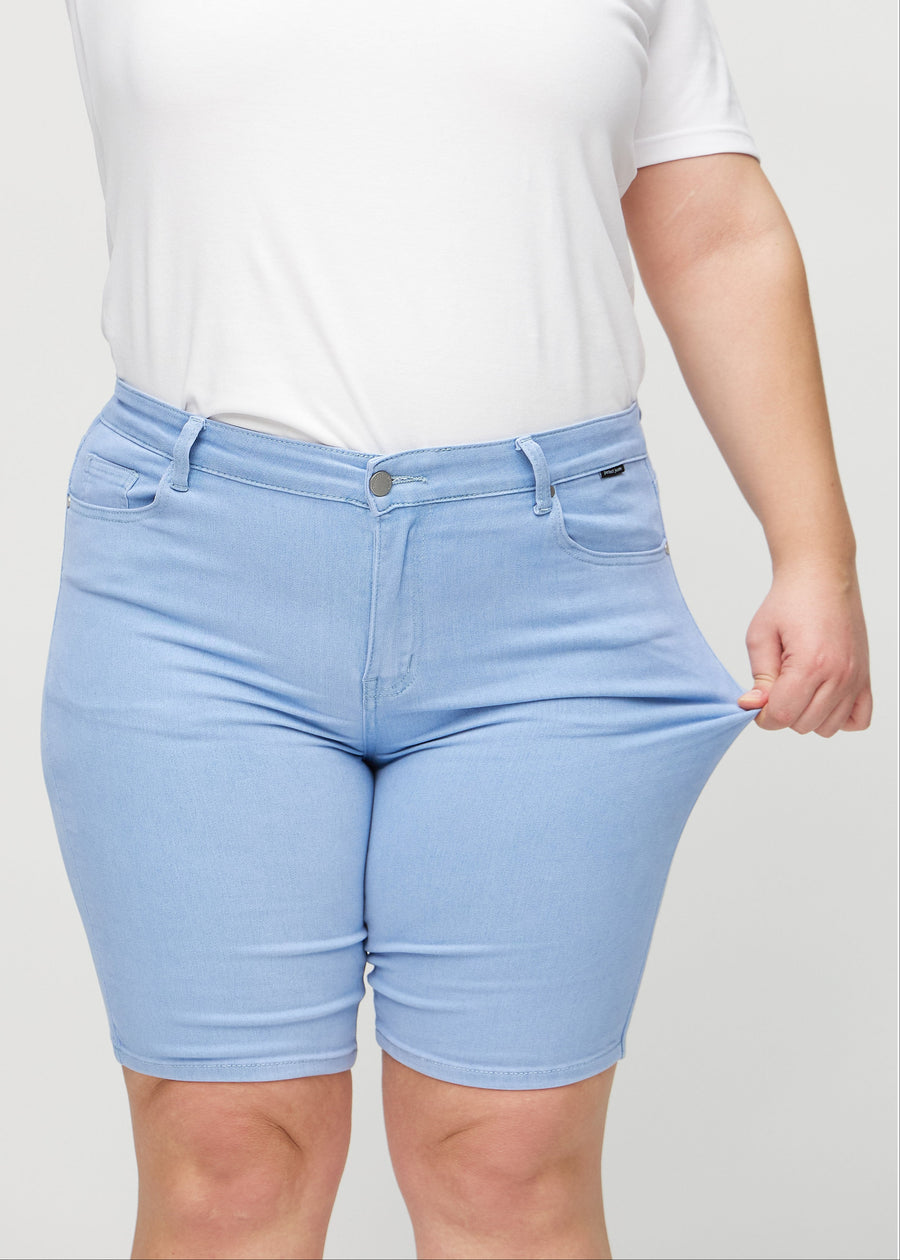 Das Plus-Size-Model zieht die Shorts am Oberschenkel auseinander, um den Stretch zu zeigen.