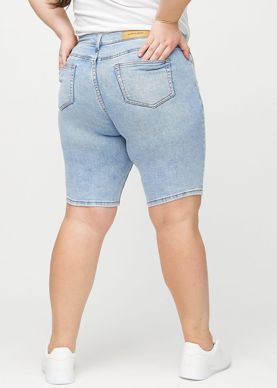 Helle Denim-skinny Middle Shorts von hinten an einem Plus-Size-Model gesehen, sodass das gesamte Produkt zu sehen ist.