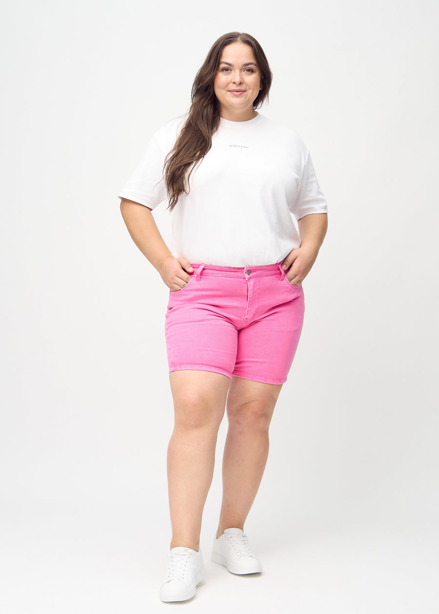 Ganzkörperbild eines Plus-Size-Models in hellrosa skinny Short Shorts.