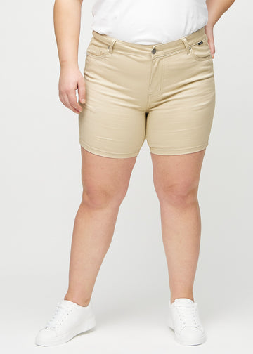 Beige skinny Short Shorts, Modellname Gazelles, eng anliegend und bis zur Mitte des Oberschenkels reichend, an einem Plus-Size-Model von vorne gesehen.