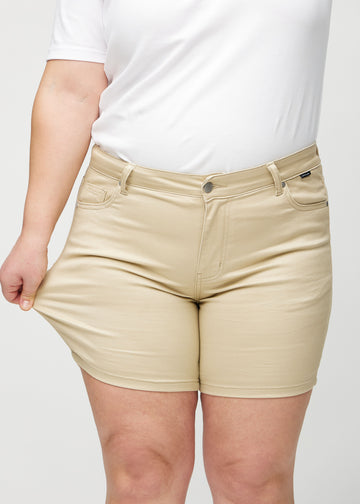 Das Plus-Size-Model zieht die Shorts am Oberschenkel auseinander, um den Stretch zu zeigen.