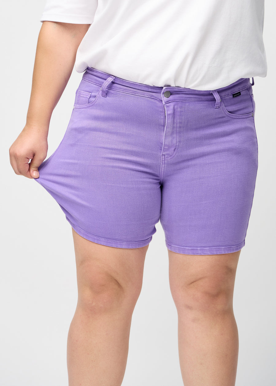 Das Plus-Size-Model zieht die Shorts am Oberschenkel auseinander, um den Stretch zu zeigen.