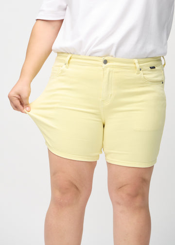 Das Plus-Size-Model zieht die Shorts am Oberschenkel auseinander, um den Stretch zu zeigen.