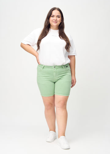Ganzkörperbild eines Plus-Size-Models in hellgrünen skinny Short Shorts.