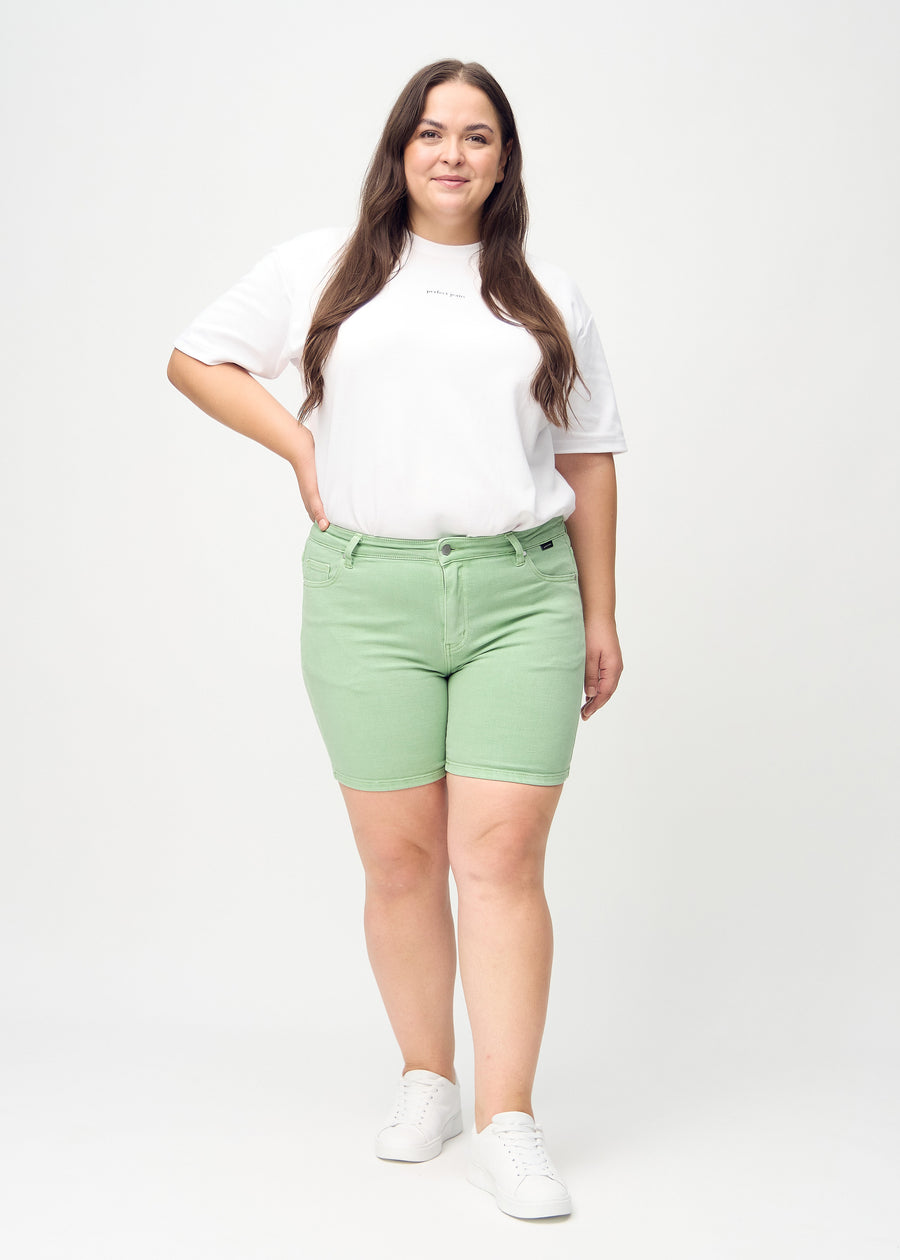 Ganzkörperbild eines Plus-Size-Models in hellgrünen skinny Short Shorts.