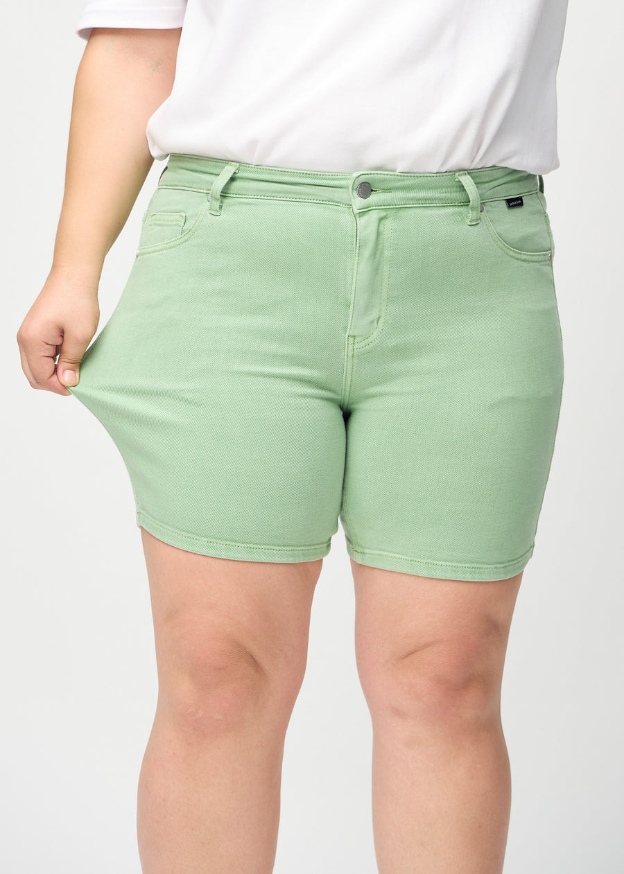 Das Plus-Size-Model zieht die Shorts am Oberschenkel auseinander, um den Stretch zu zeigen.