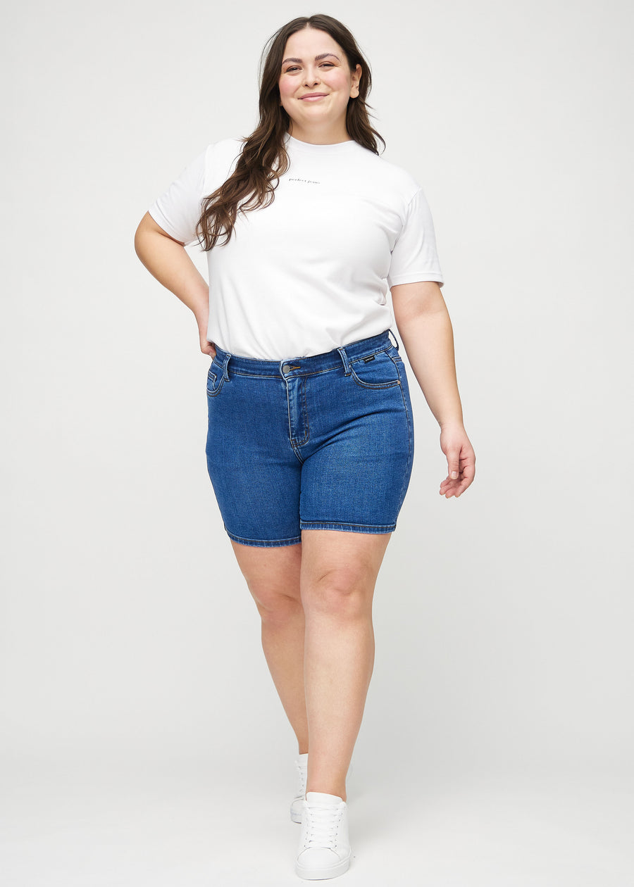 Ganzkörperbild eines Plus-Size-Models in dunklen Denim-skinny Short Shorts.