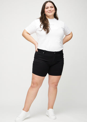 Ganzkörperbild eines Plus-Size-Models in schwarzen skinny Short Shorts.