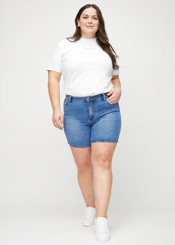 Ganzkörperbild eines Plus-Size-Models in Denim skinny Short Shorts.