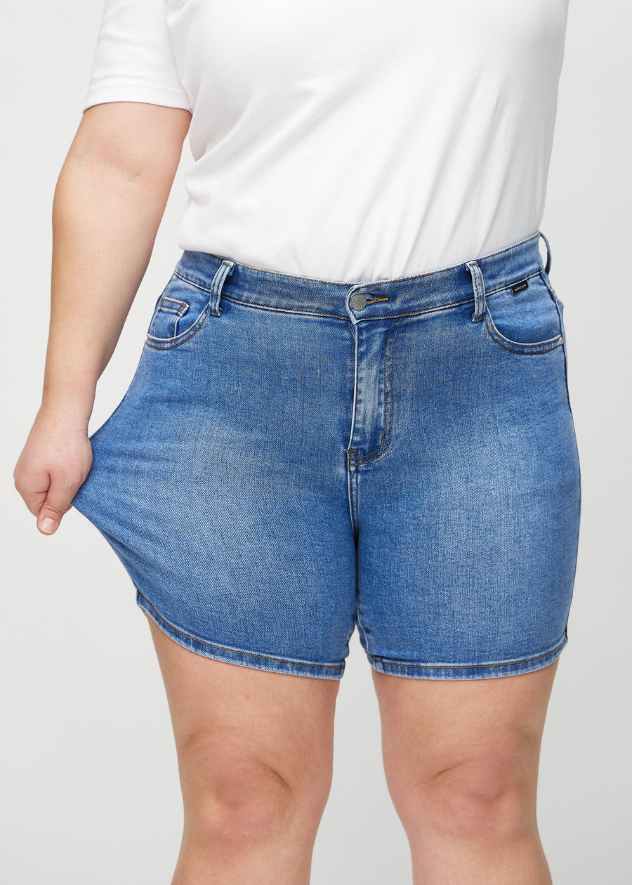 Das Plus-Size-Model dehnt die Shorts am Oberschenkel, um den Stretch zu zeigen.