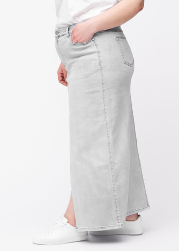 Langer hellgrauer Denimrock für Damen in der Farbe Ashes. Seitenansicht an einem Plus-Size-Model mit sichtbarem Schlitz vorne.