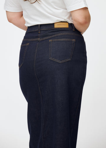 Langer tief dunkelblauer Denim-Rock für Damen in der Farbe Midnights von hinten nah auf einem Plus-Size-Model aufgenommen, um Passform und Details zu zeigen.