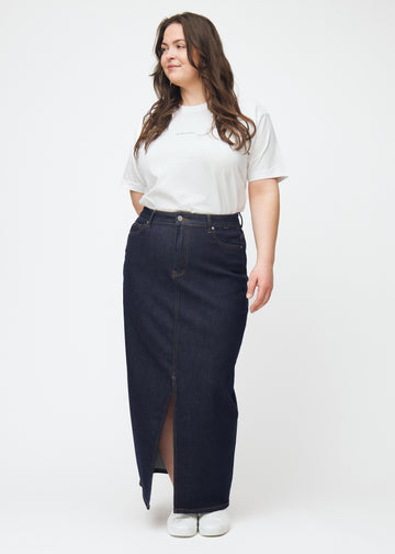 Ganzkörperbild eines Plus-Size-Models in einem langen tief dunkelblauen Denim-Rock für Damen in der Farbe Midnights mit Schlitz vorne.