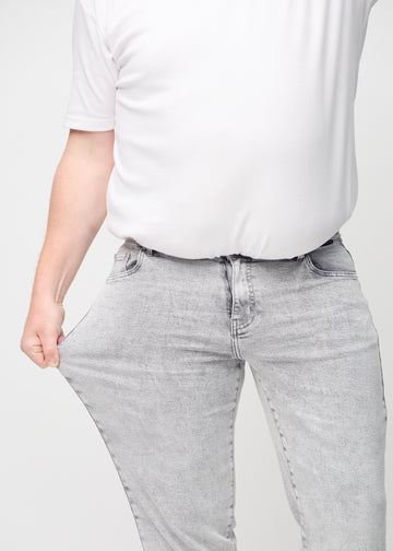 Das Plus-Size-Model zieht die Jeans am Oberschenkel auseinander, um den Stretch zu zeigen.