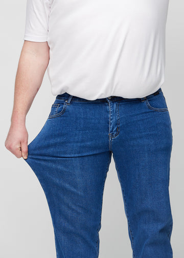 Das Plus-Size-Model dehnt die Jeans am Oberschenkel, um den Stretch zu zeigen.