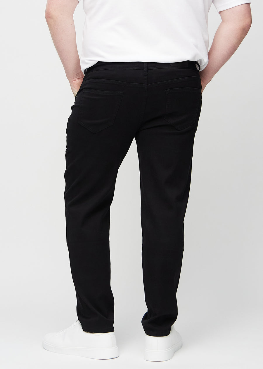 Schwarze regular jeans von hinten an einem Plus-Size-Model gesehen, damit man das ganze Produkt sehen kann.