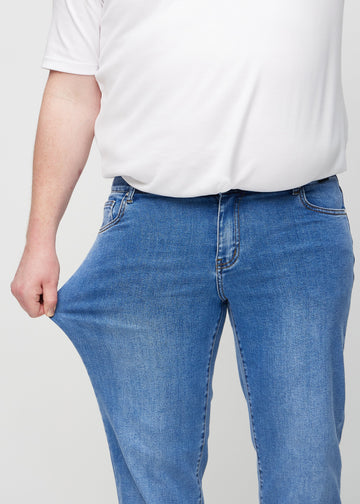 Das Plus-Size-Model dehnt die Jeans am Oberschenkel, um den Stretch zu zeigen.