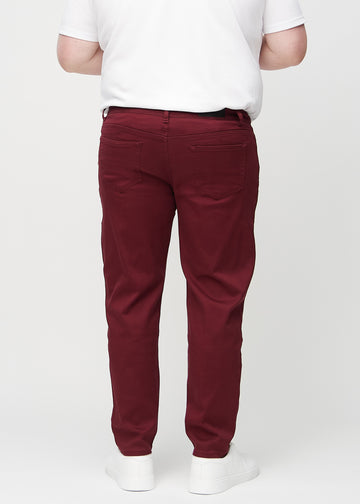 Dunkelrote regular jeans von hinten an einem Plus-Size-Model gesehen, sodass man das gesamte Produkt sehen kann.