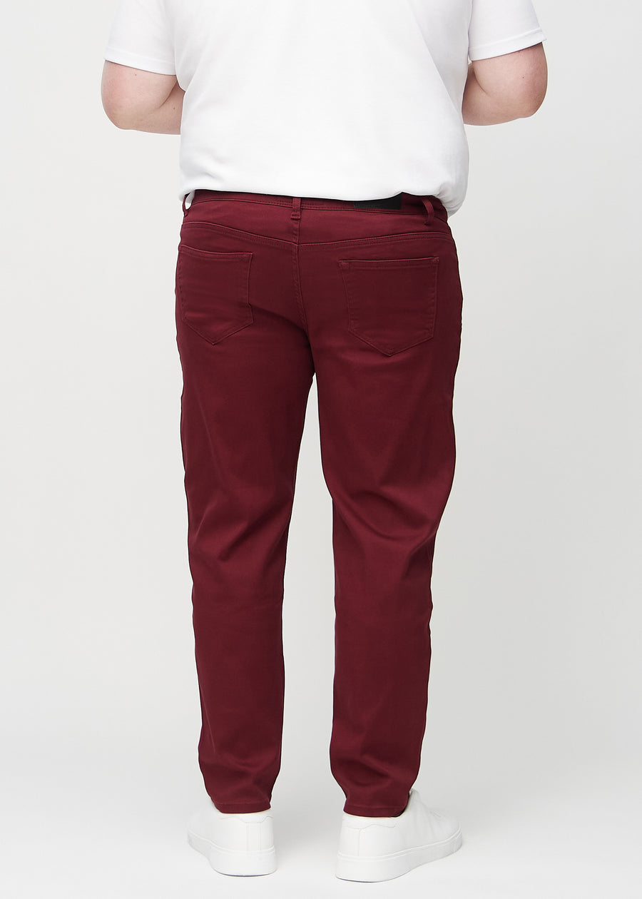 Dunkelrote regular jeans von hinten an einem Plus-Size-Model gesehen, sodass man das gesamte Produkt sehen kann.