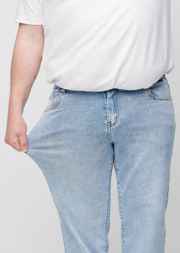 Das Plus-Size-Model dehnt die Jeans am Oberschenkel, um den Stretch zu zeigen.
