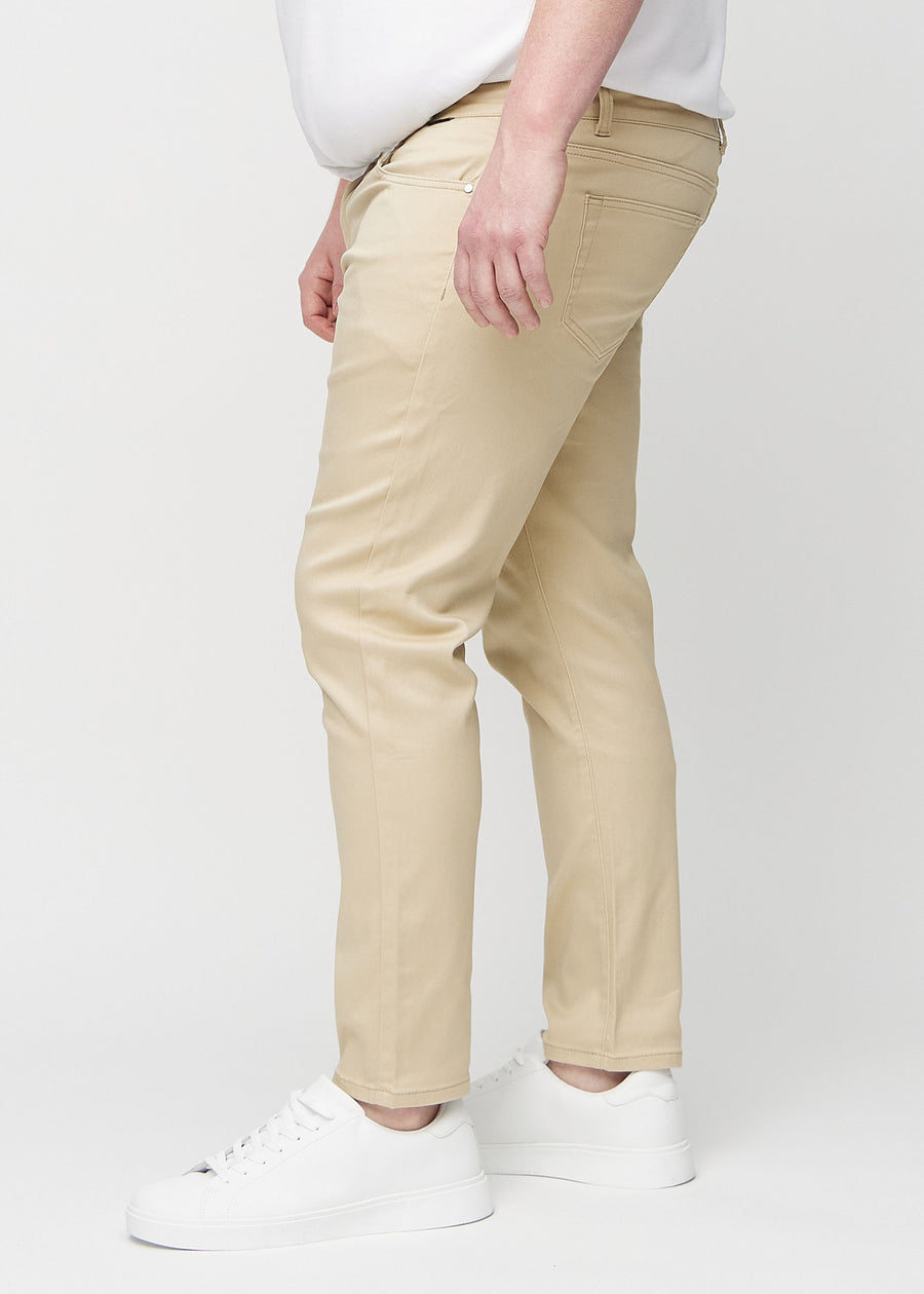 Beigefarbene Jeans im Slim Fit, von der Seite an einem Plus-Size-Model gesehen.