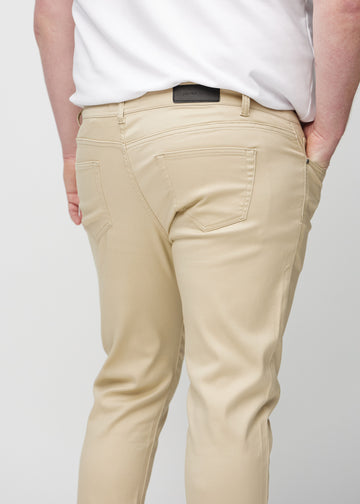 Nahaufnahme von hinten von beigefarbene Jeans im Slim Fit an einem Plus-Size-Model, die Details zeigt.