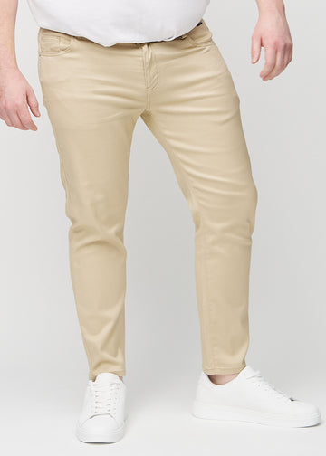 Beigefarbene Jeans im Slim Fit, Modell Gazelles, die an einem Plus-Size-Model eng an den Beinen anliegen, von vorne gesehen.