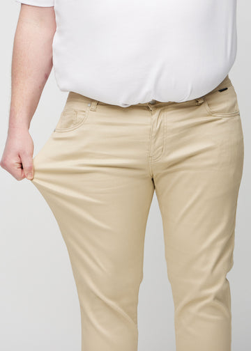 Ein Plus-Size-Model dehnt die Jeans am Oberschenkel, um den Stretch des Materials zu zeigen.