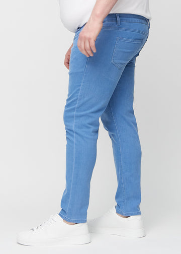 Blaue Jeans im Slim Fit, von der Seite an einem Plus-Size-Model gesehen.