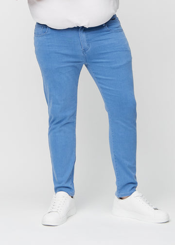 Blaue Jeans im Slim Fit, Modell Geraniums, die an einem Plus-Size-Model eng an den Beinen anliegen, von vorne gesehen.
