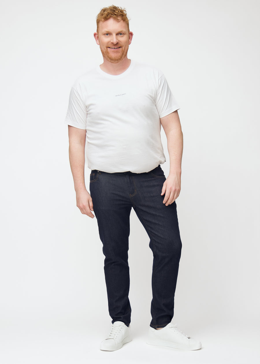 Ganzkörperbild eines Plus-Size-Models in tief dunkelblauer Denim jeans für Herren in der Farbe Midnights mit slim Passform.