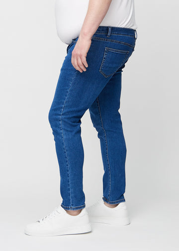 Dunkelblaue Denim-Jeans im Slim Fit, von der Seite an einem Plus-Size-Model gesehen.