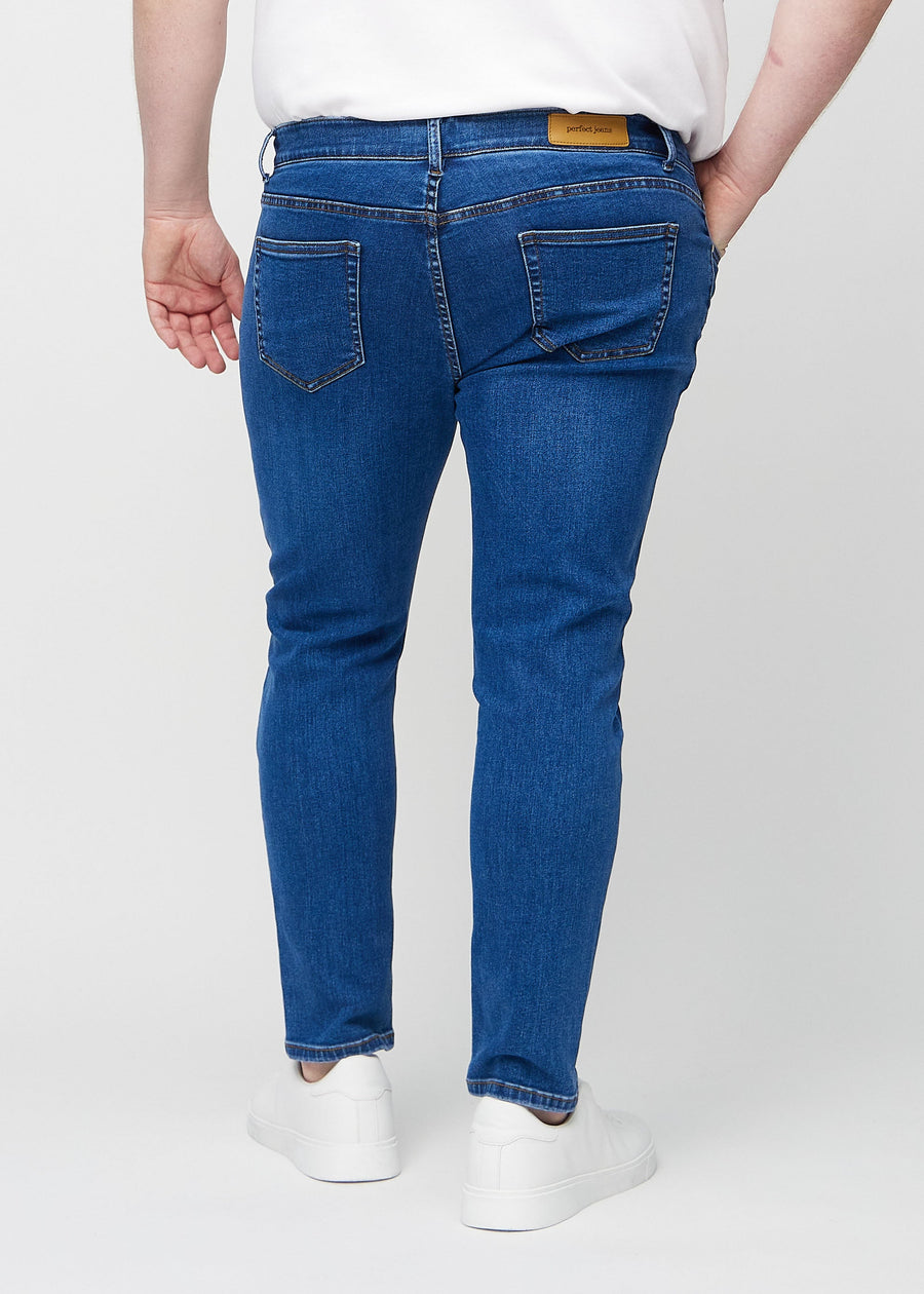 Dunkelblaue Denim-Jeans im Slim Fit, von hinten an einem Plus-Size-Model gesehen, um die gesamte Jeans zu zeigen.