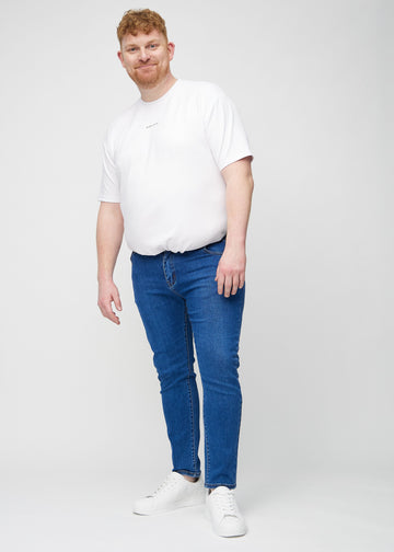 Ganzkörperaufnahme eines Plus-Size-Models in dunkelblaue Denim-Jeans im Slim Fit.
