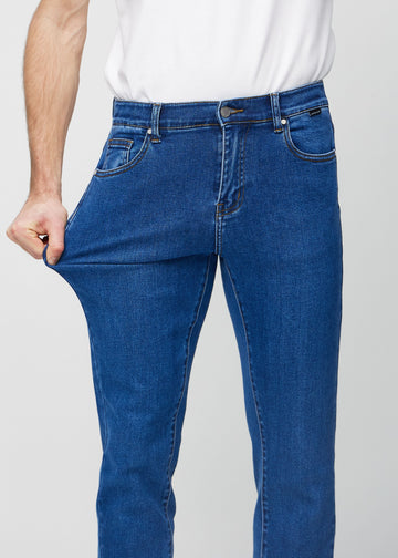 Ein Model dehnt die Jeans am Oberschenkel, um den Stretch des Materials zu zeigen.