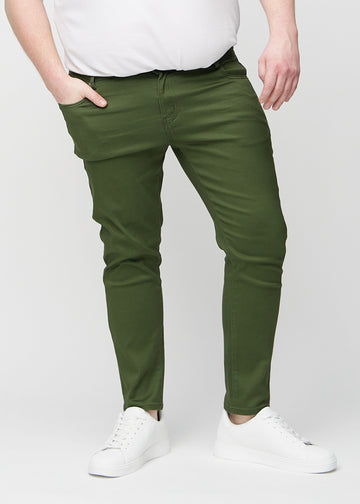 Dunkelgrüne Jeans im Slim Fit, Modell Renewals, die an einem Plus-Size-Model eng an den Beinen anliegen, von vorne gesehen.