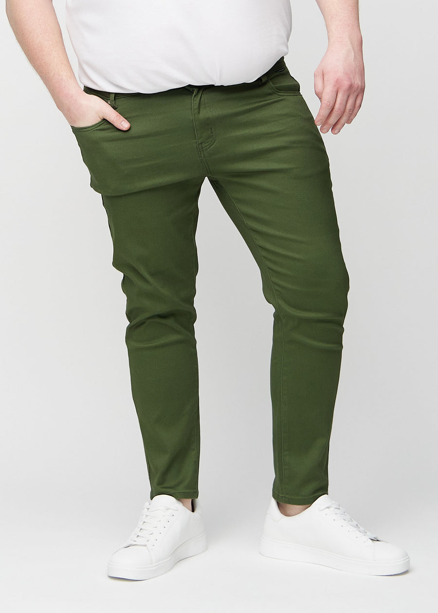 Dunkelgrüne Jeans im Slim Fit, Modell Renewals, die an einem Plus-Size-Model eng an den Beinen anliegen, von vorne gesehen.