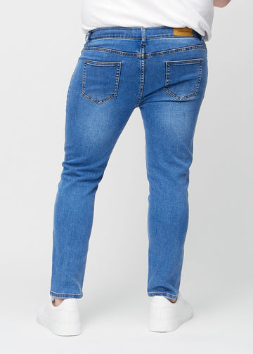 Blaue Denim-Jeans im Slim Fit, von hinten an einem Plus-Size-Model gesehen, um die gesamte Jeans zu zeigen.