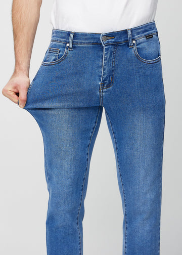 Ein Model dehnt die Jeans am Oberschenkel, um den Stretch des Materials zu zeigen.