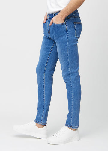 Blaue Denim-Jeans im Slim Fit, von der Seite an einem Model gesehen.