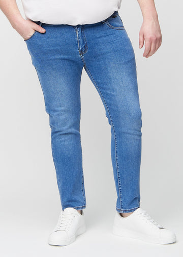 Blaue Denim-Jeans im Slim Fit, Modell Rivers, die an einem Plus-Size-Model eng an den Beinen anliegen, von vorne gesehen.