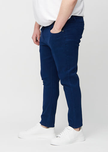 Dunkelblaue Jeans im Slim Fit, von der Seite an einem Plus-Size-Model gesehen.