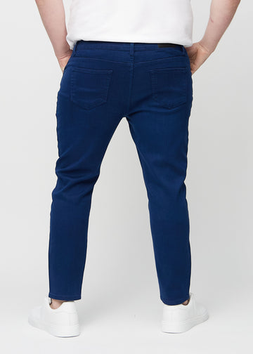 Dunkelblaue Jeans im Slim Fit, von hinten an einem Plus-Size-Model gesehen, um die gesamte Jeans zu zeigen.