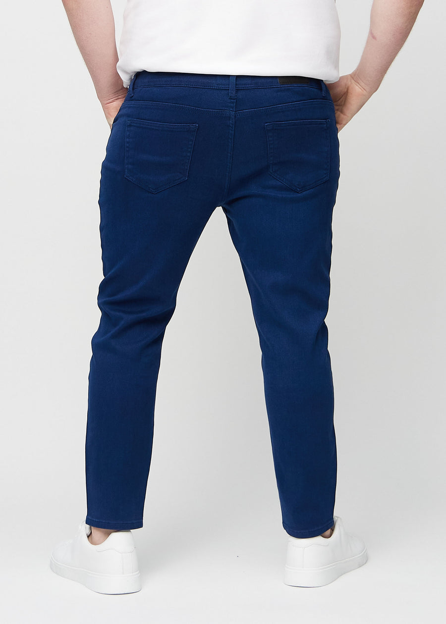 Dunkelblaue Jeans im Slim Fit, von hinten an einem Plus-Size-Model gesehen, um die gesamte Jeans zu zeigen.