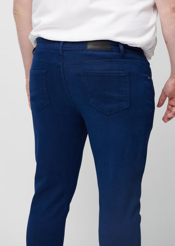 Nahaufnahme von hinten von dunkelblaue Jeans im Slim Fit an einem Plus-Size-Model, die Details zeigt.