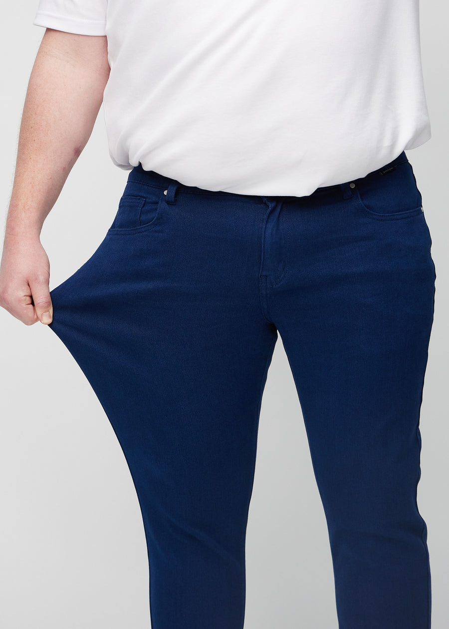 Ein Plus-Size-Model dehnt die Jeans am Oberschenkel, um den Stretch des Materials zu zeigen.